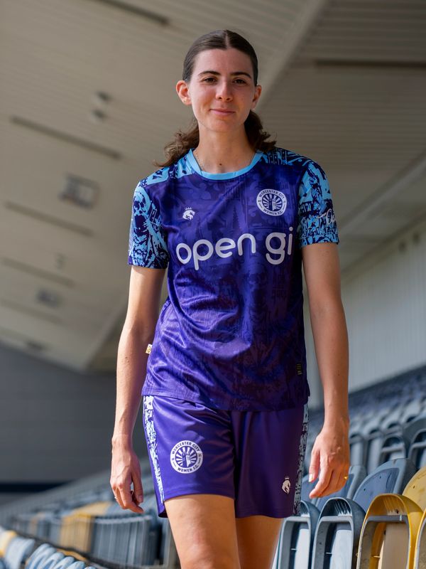 Female athlete in a purple and blue sports uniform at a stadium.