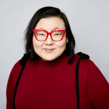 Person with black hair and red glasses wearing a red top.