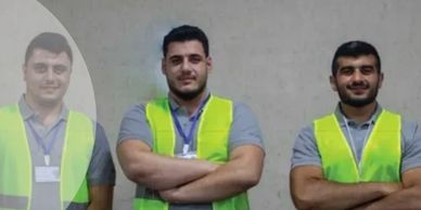 Three men in safety vests pose with arms crossed.