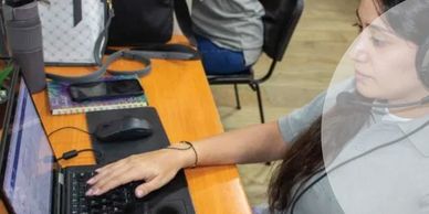 A woman working on a laptop wearing headphones.