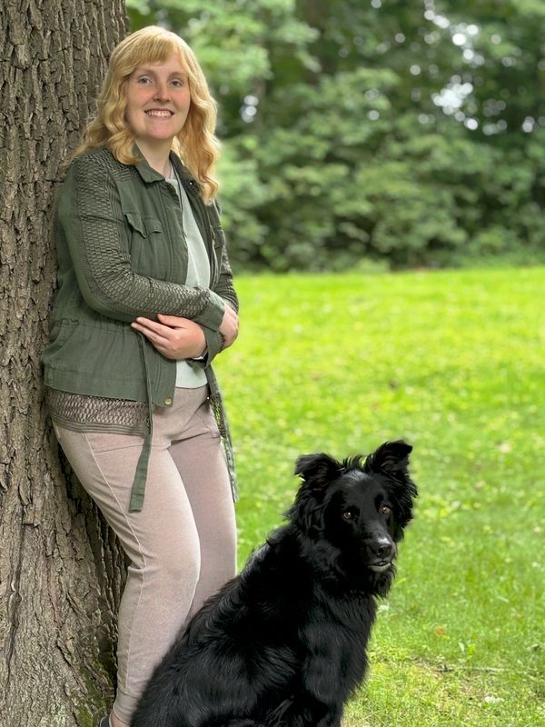 Sara Harner with a black dog during an outdoor pet photography session in Central Indiana.