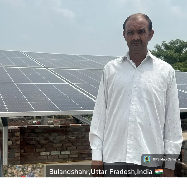 Man standing near solar panels in Bulandshahr, Uttar Pradesh, India.