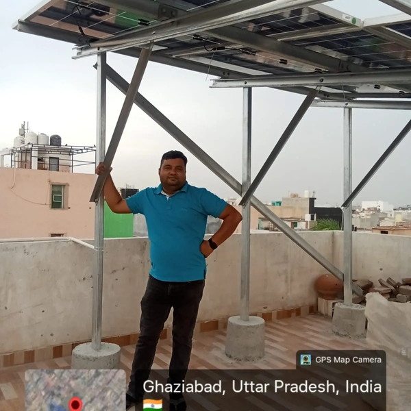 Man standing under solar panels on a rooftop.