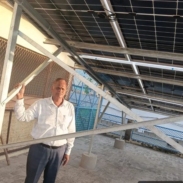Man standing under solar panels in Dadri, Uttar Pradesh, India.