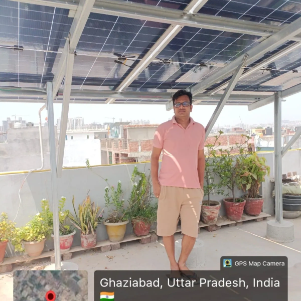 Man standing under solar panels on a rooftop in Ghaziabad, India.