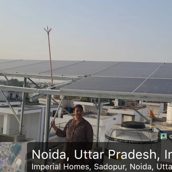 Woman standing beside rooftop solar panels in Noida, India.