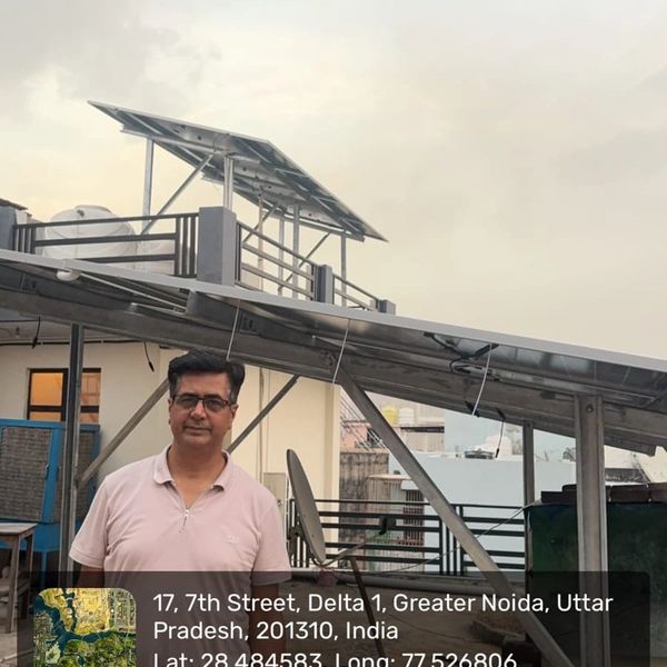 Man standing on rooftop with solar panels in Greater Noida, India.