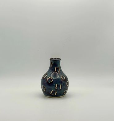Small dark blue patterned vase on a plain background.