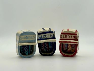 Three small ceramic sardine cans in different colors.