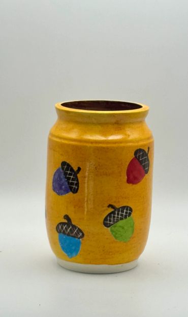 Yellow ceramic vase with colorful acorn designs.