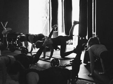 Group of people exercising indoors in dim lighting.