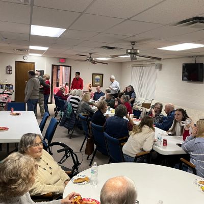 A group of people socializing and eating in a community room.