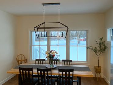 Dining room with wooden table and chairs under modern light fixture.