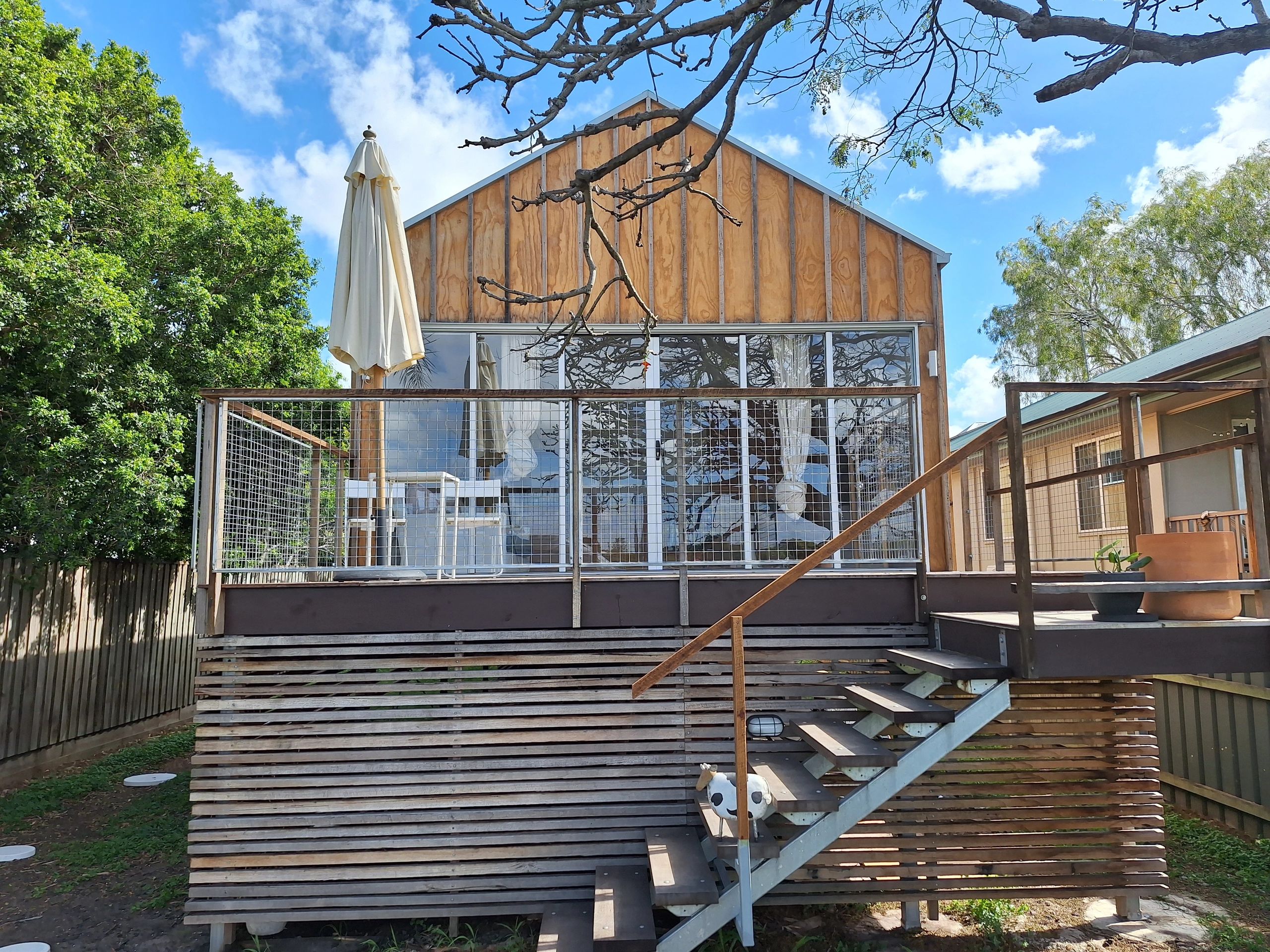 Modern wooden house with a glass-fronted balcony and outdoor stairs.