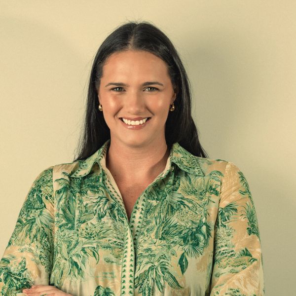Smiling woman in a green patterned blouse against a plain background.