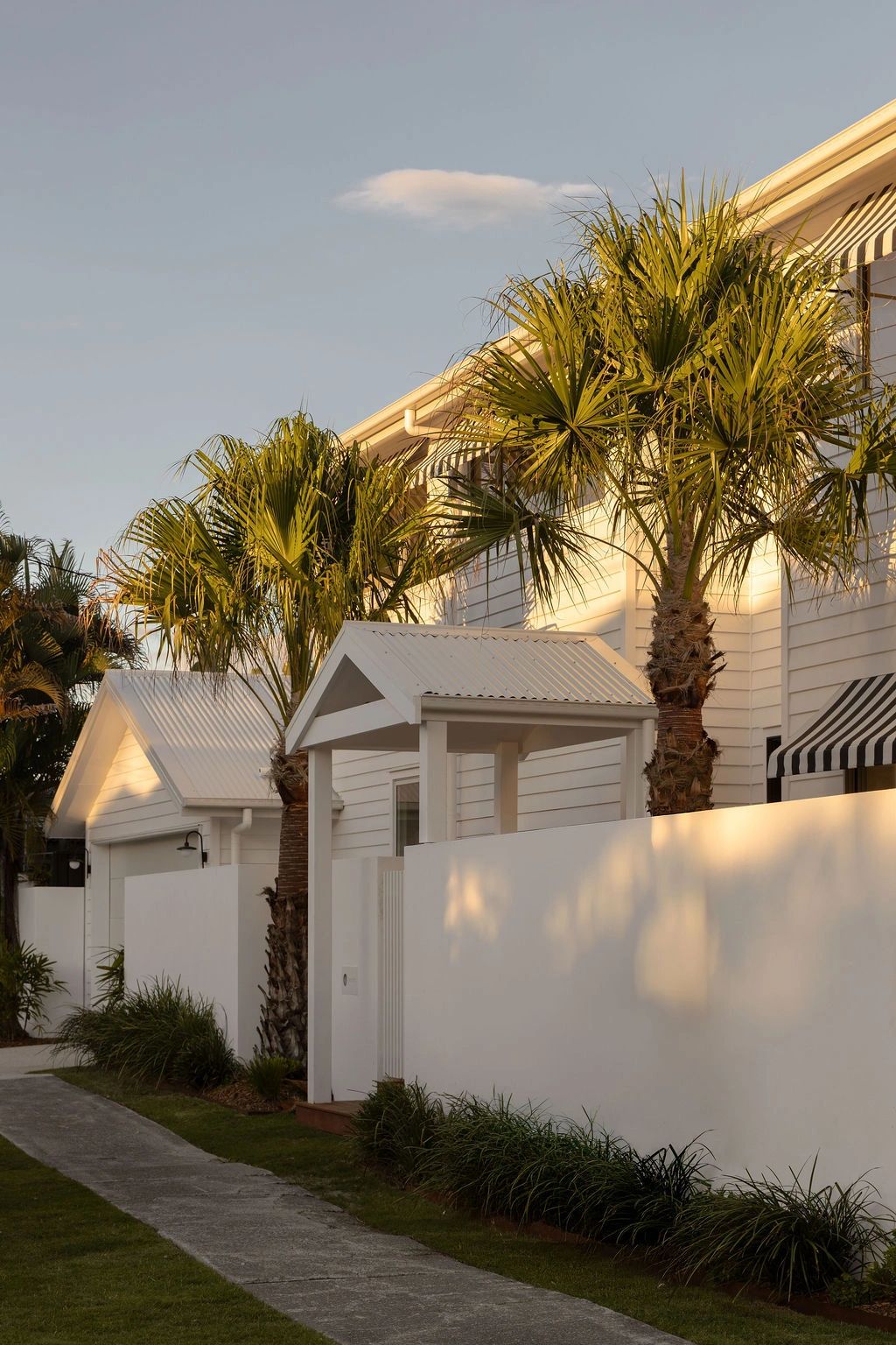 White houses with palm trees and a clear sky at sunset.