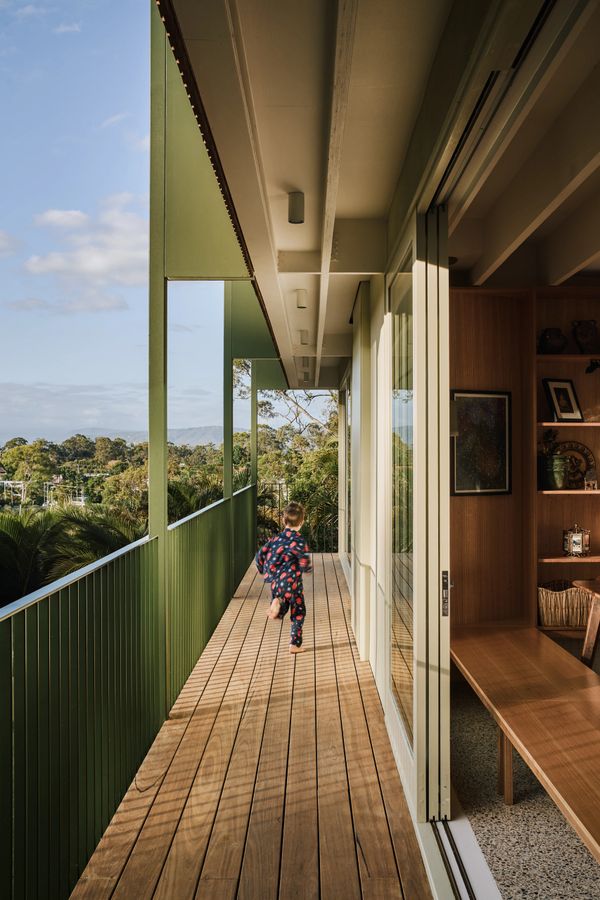 Child in pajamas running on a wooden balcony with green railings.