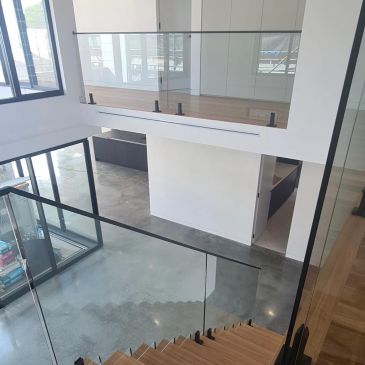 Modern interior with glass railings and wooden stairs.