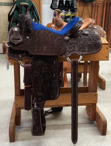 Intricately tooled leather saddle with blue seating.