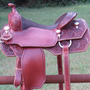 Decoratively tooled leather saddle on a metal rail.