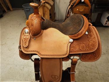 Detailed leather horse saddle with floral carving.