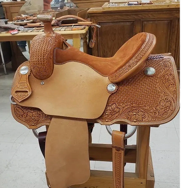 Intricately tooled leather saddle on a wooden stand.