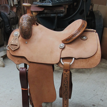 A detailed leather saddle on a stand in a workshop.