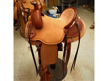 A brown leather western saddle with detailed stitching.
