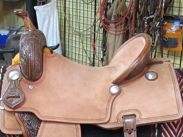 Leather horse saddle on a patterned blanket.