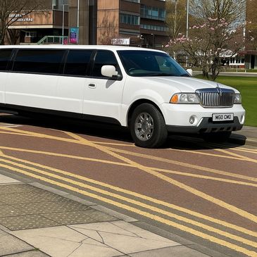 A white stretch limousine parked on a street with yellow road markings.