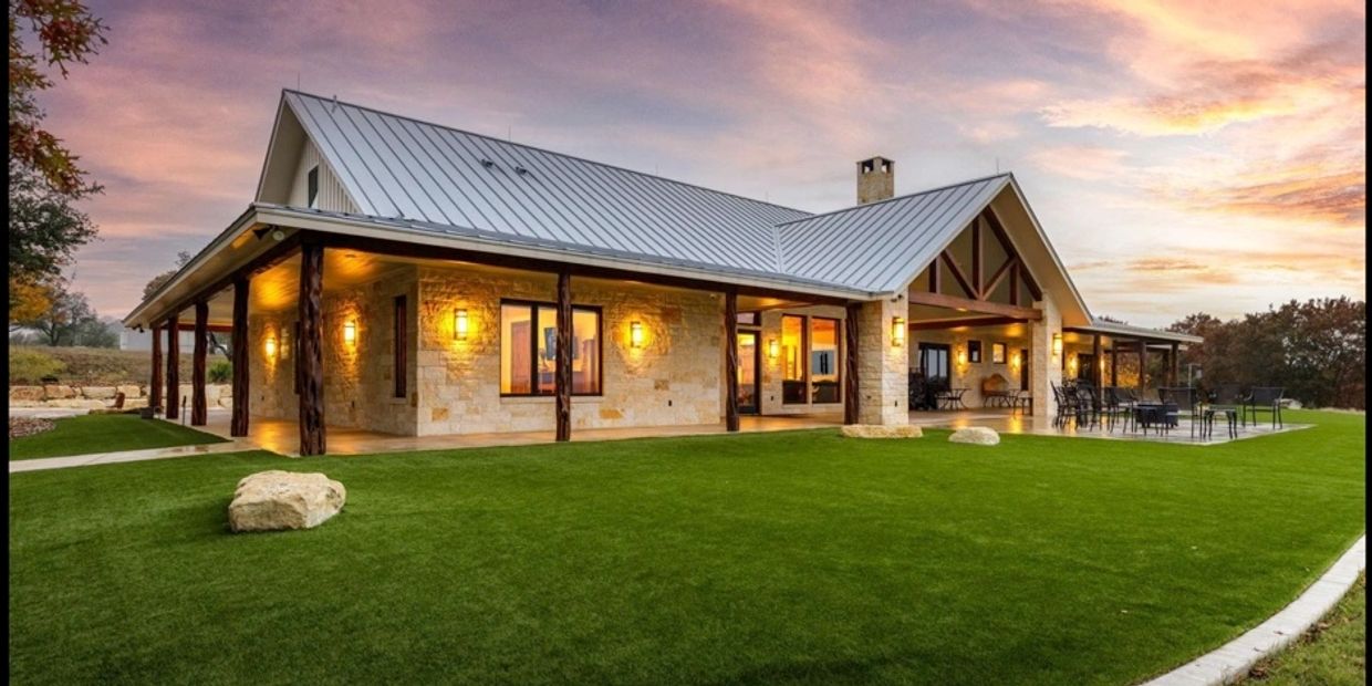 Modern house with stone walls and metal roof at sunset.