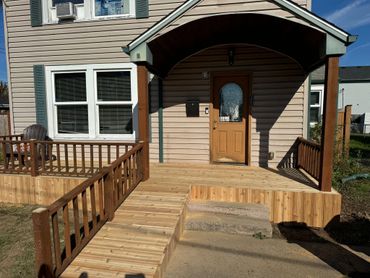 New wooden ramp and deck leading to a house entrance.