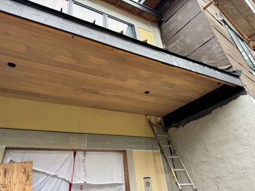 A building under construction with a wooden ceiling and a ladder leaning against the wall.