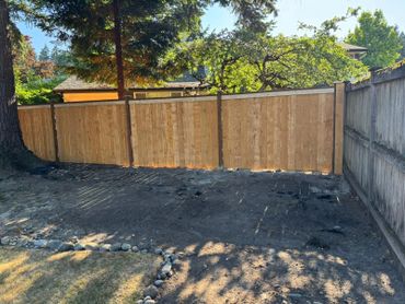 New wooden fence panels installed in a backyard under sunlight.