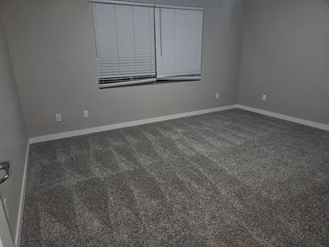 Empty room with gray carpet and closed window blinds.