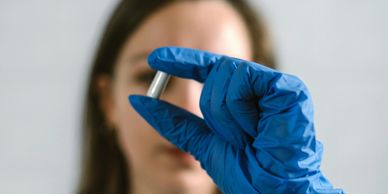 Person holding a capsule pill with a gloved hand.