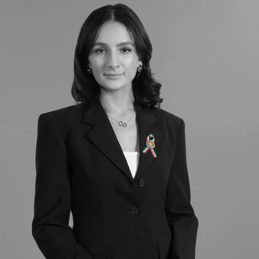 Professional woman in a black blazer with a ribbon pin.
