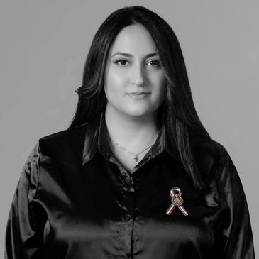 Black and white portrait of a woman wearing a dark blouse with a ribbon pin.