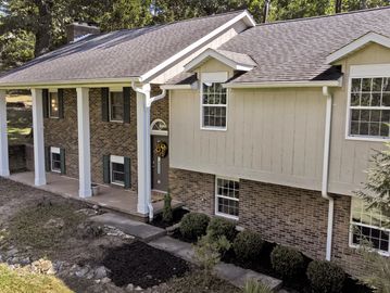 Brick and siding house with white pillars and landscaped front yard.