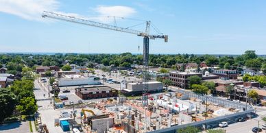 A construction site with a tall crane in a suburban area under a clear sky.