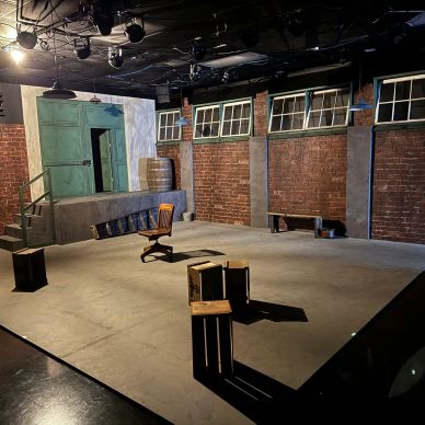 Empty stage set with brick walls and minimal furniture