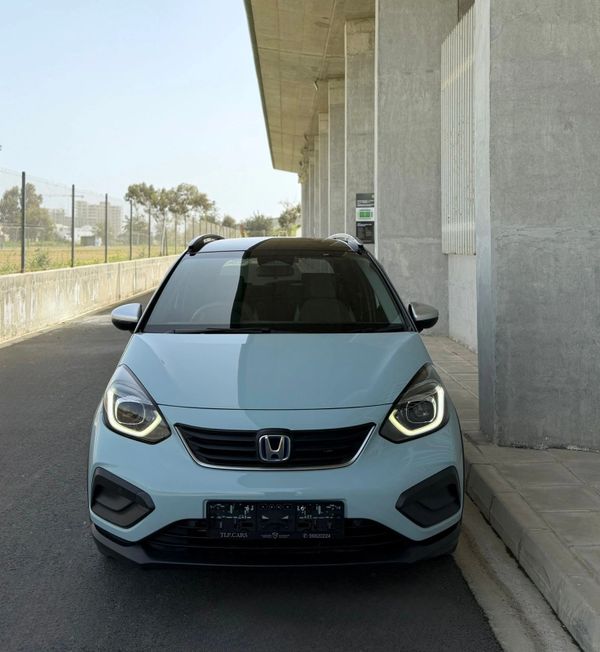 Front view of a modern light blue Honda car with its headlights on.