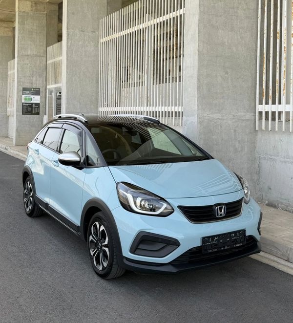 Light blue Honda compact crossover parked on the street near a concrete building.