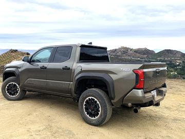 A Toyota Tacoma TRD Off-Road truck parked on a dirt hill with mountainous background.