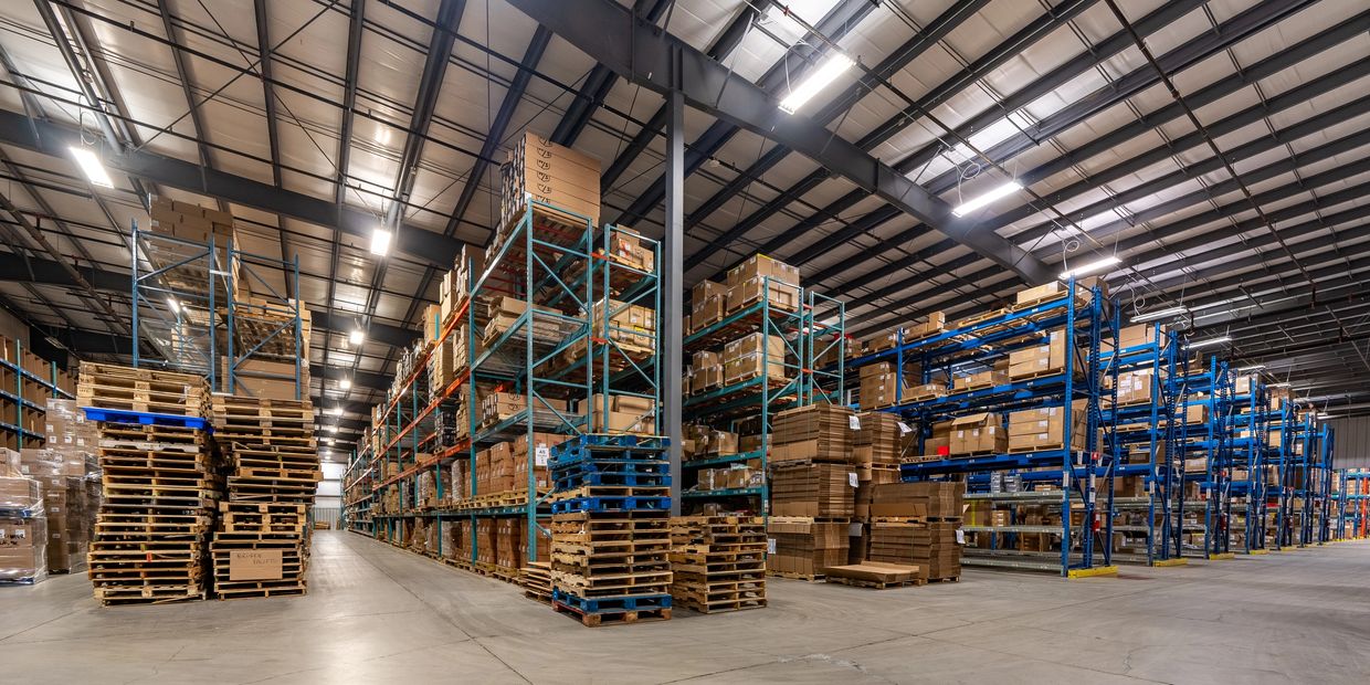 Large warehouse with stacked pallets and boxed inventory on metal shelving.