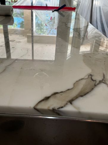 Close-up of a polished marble countertop with reflections and a roll of paper towel.