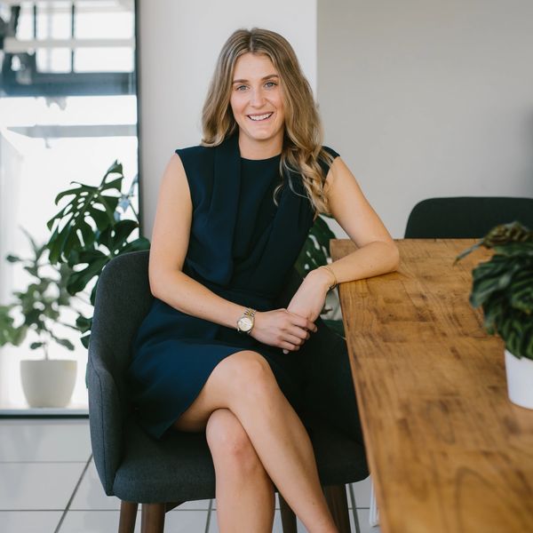 Young woman sitting confidently at a wooden table in a modern office.