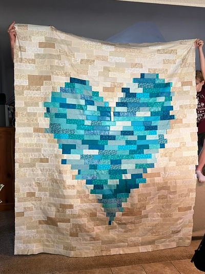 top of the quilt in tan blocks with turquoise  blocks in the shape of a heart in the middle