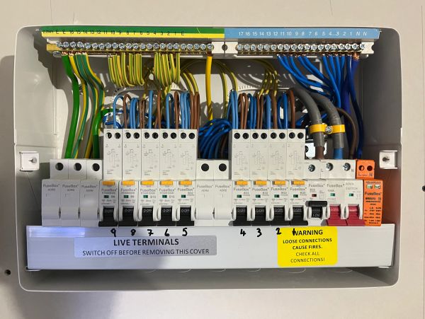 Electric breaker panel with labeled terminals and warning signs.