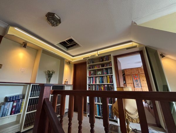 Cozy home library with wooden railing and ceiling light.